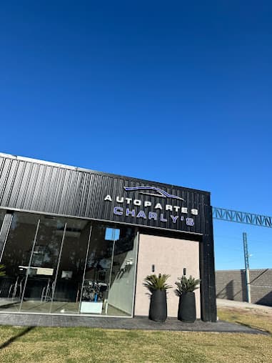Fachada negra con el cartel de Autopartes Charly's bajo el cielo despejado