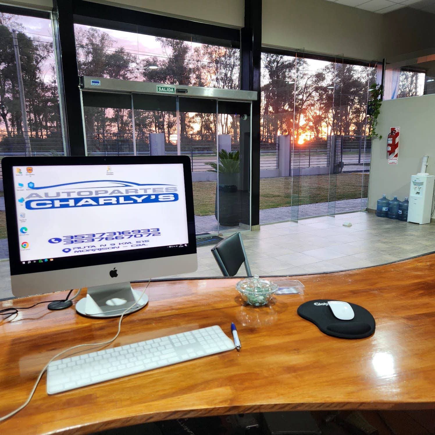 Puesto de atención del salón con el logo en pantalla y el ventanal al atardecer